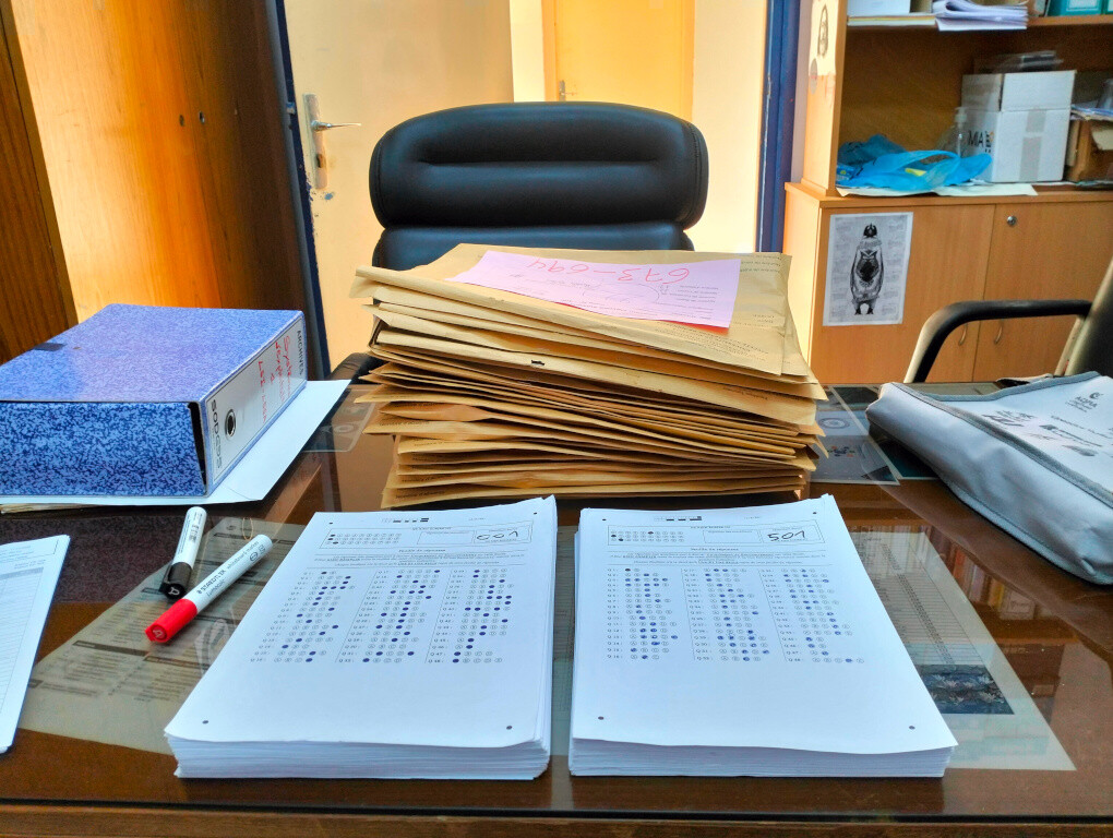 Des enveloppes avec des copies de feuilles de réponses sur un bureau.